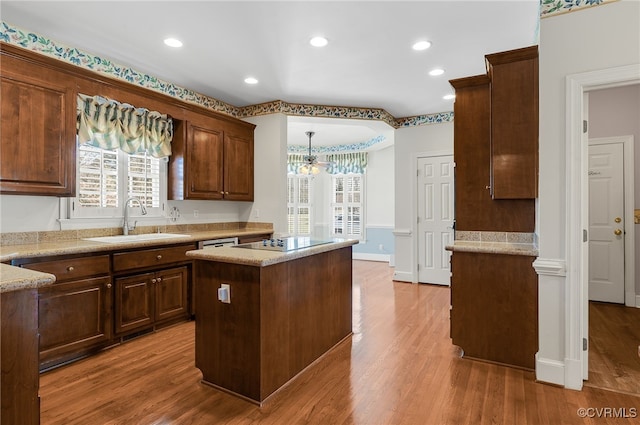 kitchen featuring light wood-type flooring, a sink, black electric cooktop, and a wealth of natural light
