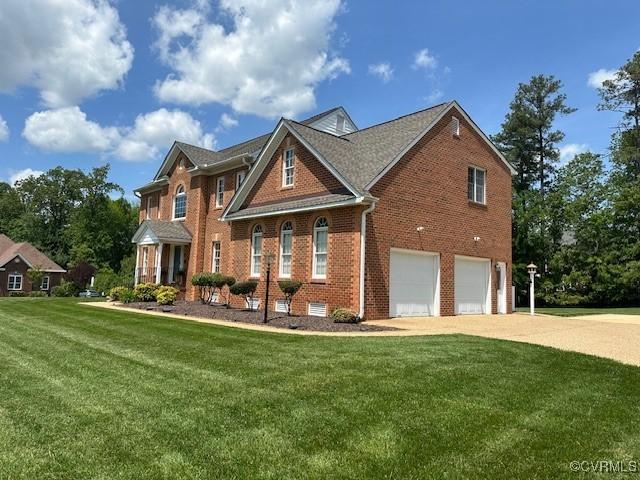 view of front of house featuring brick siding, a garage, a front lawn, and driveway