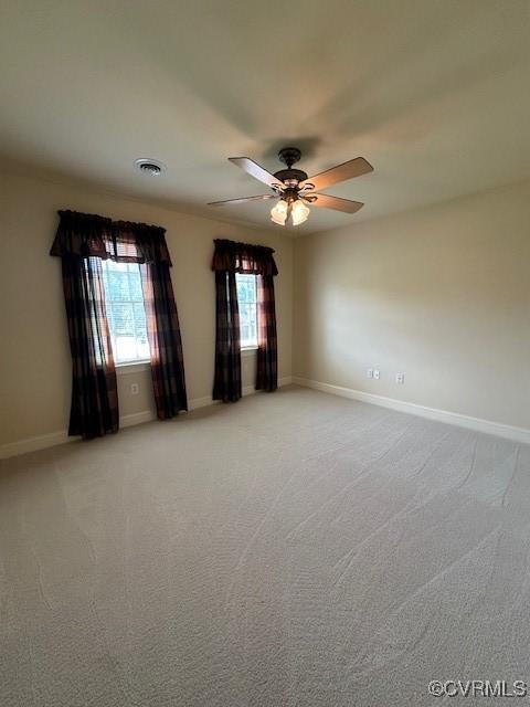 spare room with baseboards, a ceiling fan, visible vents, and light carpet