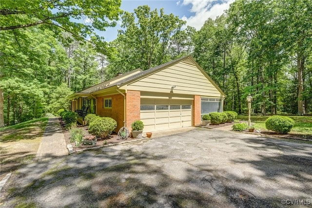 view of side of property featuring brick siding, a garage, and driveway