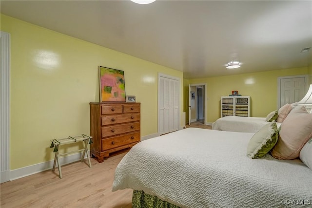 bedroom with light wood-type flooring, baseboards, and a closet