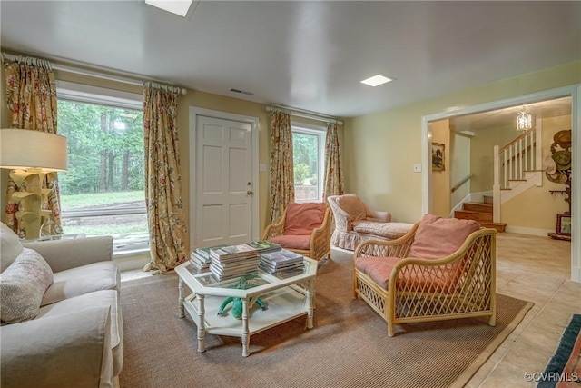 living area with healthy amount of natural light, stairway, and tile patterned floors