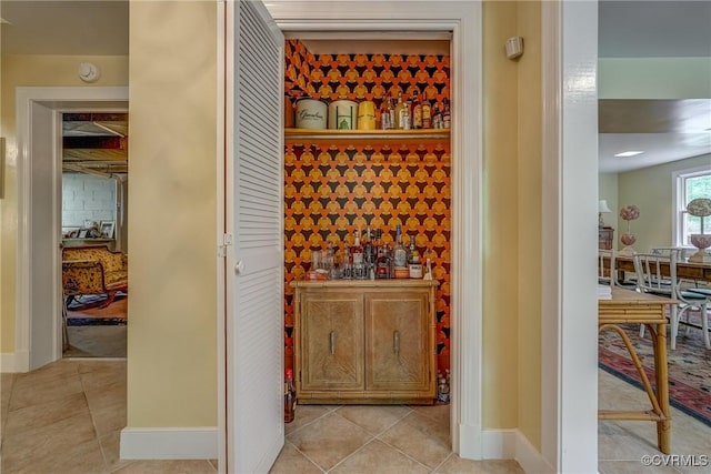 wine cellar featuring baseboards, light tile patterned flooring, and a dry bar