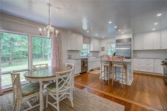 dining space with wood-type flooring, a chandelier, and recessed lighting