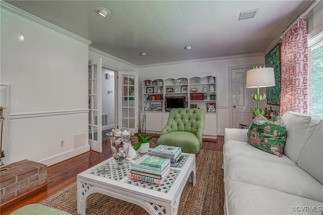 living area with wood finished floors, crown molding, french doors, baseboards, and built in shelves