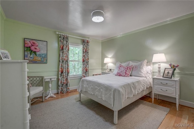 bedroom with crown molding, wood finished floors, and baseboards