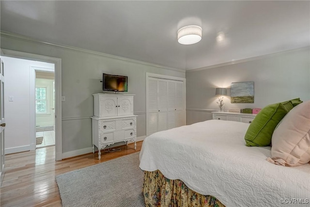 bedroom with crown molding, light wood finished floors, a closet, and baseboards