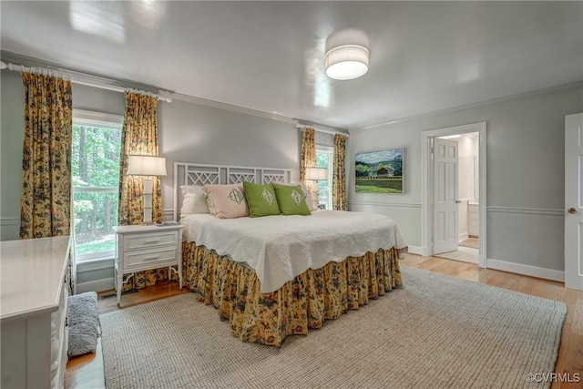 bedroom featuring ornamental molding, wood finished floors, and ensuite bath