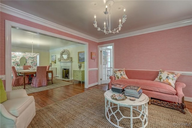 living area with a chandelier, wood finished floors, crown molding, plenty of natural light, and baseboards