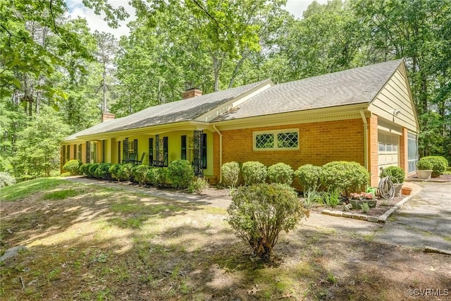 view of front of house featuring brick siding, a chimney, an attached garage, and a shingled roof