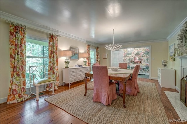 dining area with a chandelier, ornamental molding, light wood finished floors, and baseboards