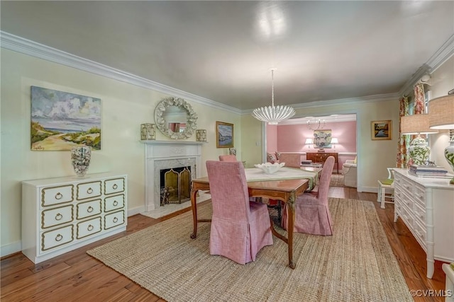 dining area featuring ornamental molding, wood finished floors, a premium fireplace, and baseboards