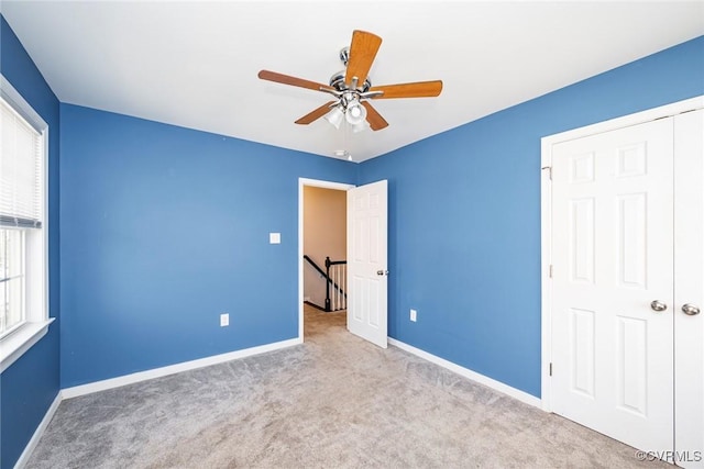 unfurnished bedroom featuring carpet floors, baseboards, and a ceiling fan