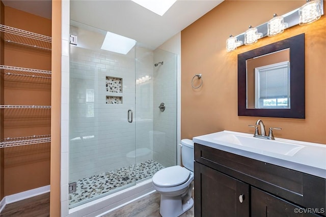 full bathroom with a walk in closet, toilet, wood finished floors, a skylight, and a stall shower