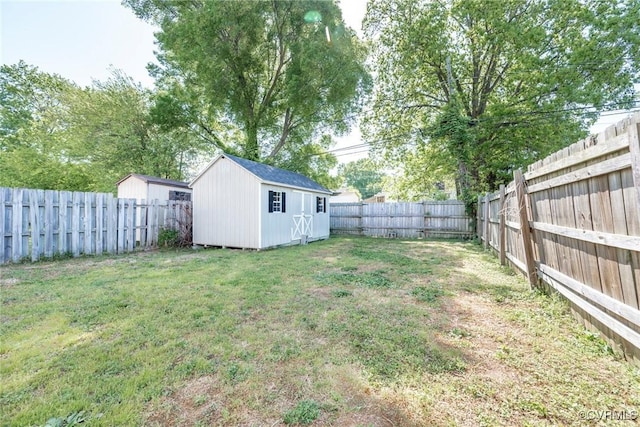 view of yard featuring an outdoor structure, a fenced backyard, and a storage unit