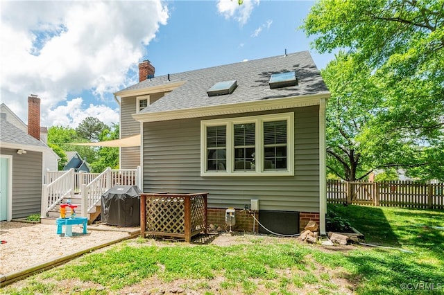 back of property featuring a lawn and fence