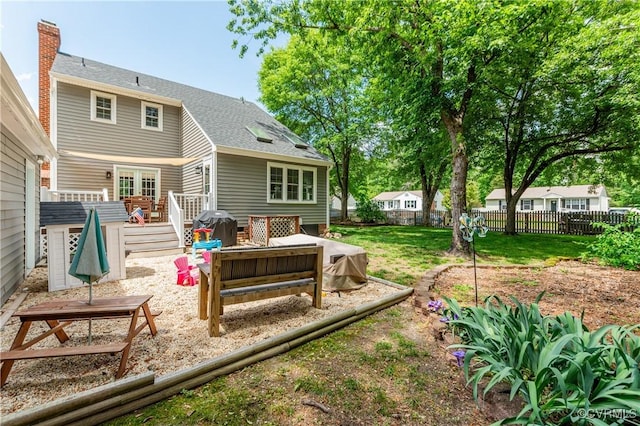 back of property with a yard, a wooden deck, a chimney, and fence