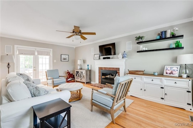 living area with crown molding, light wood-style floors, a brick fireplace, and ceiling fan