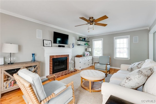living area with a fireplace, crown molding, ceiling fan, and wood finished floors