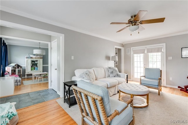 living room with crown molding, baseboards, ceiling fan, and wood finished floors