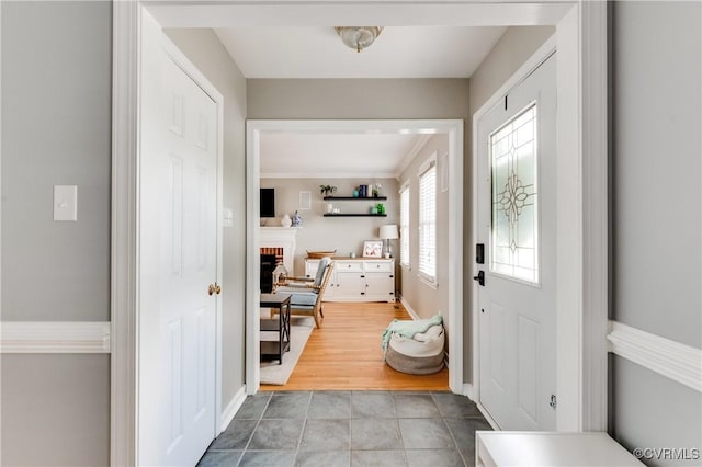 tiled entryway with a fireplace and baseboards