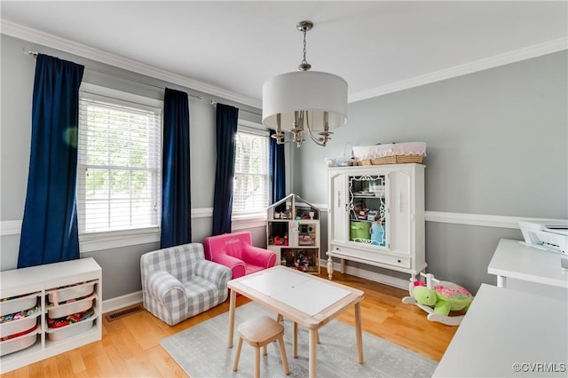 sitting room with crown molding, an inviting chandelier, visible vents, and wood finished floors