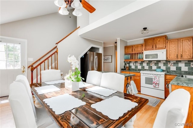 dining space with vaulted ceiling, light wood-style floors, stairway, and ceiling fan