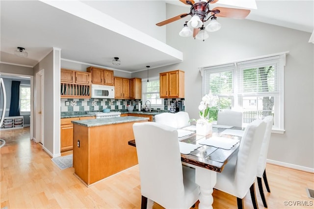 kitchen featuring a center island, stove, a sink, white microwave, and light wood-style floors