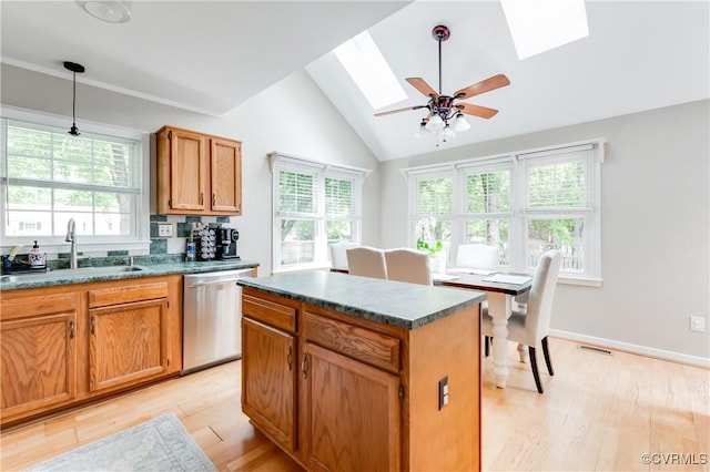 kitchen featuring light wood-style flooring, lofted ceiling with skylight, a sink, dark countertops, and dishwasher
