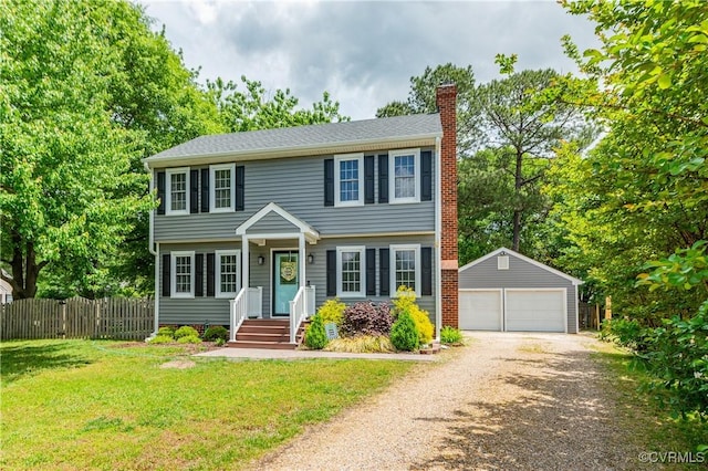 colonial home with a chimney, fence, a front yard, an outbuilding, and a detached garage