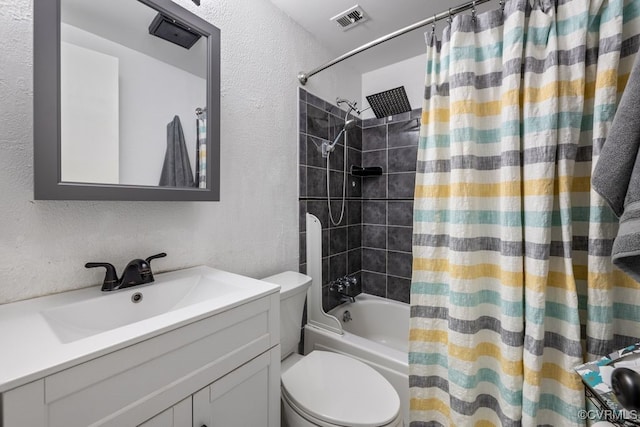 bathroom with a textured wall, shower / bath combo, vanity, and toilet