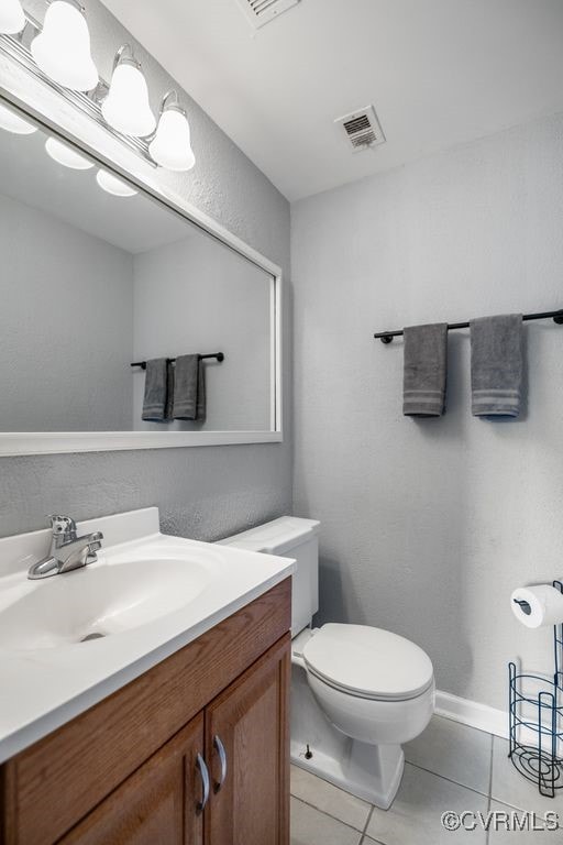 half bathroom featuring tile patterned flooring, toilet, and vanity