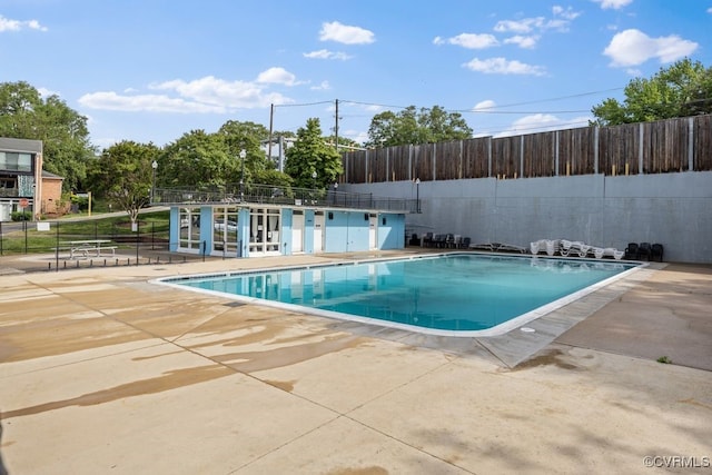 community pool with fence and a patio