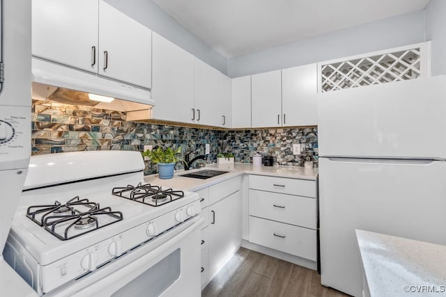 kitchen featuring white appliances, under cabinet range hood, a sink, light countertops, and white cabinets