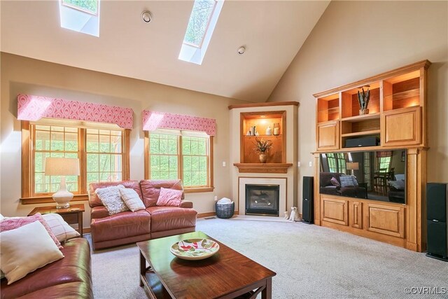 carpeted living room featuring a skylight, a glass covered fireplace, and high vaulted ceiling