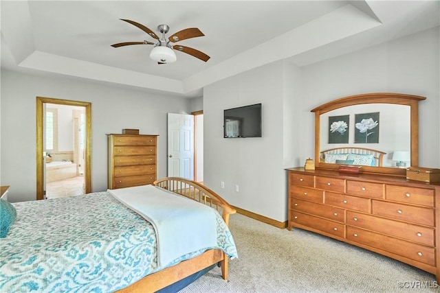 bedroom with ceiling fan, carpet floors, baseboards, connected bathroom, and a tray ceiling