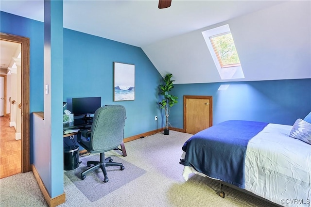 carpeted bedroom featuring baseboards, ceiling fan, and vaulted ceiling with skylight