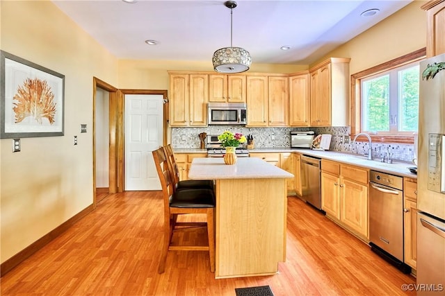 kitchen featuring light countertops, a sink, light brown cabinets, and stainless steel appliances