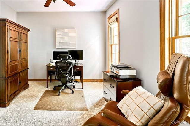 carpeted office space featuring baseboards and a ceiling fan