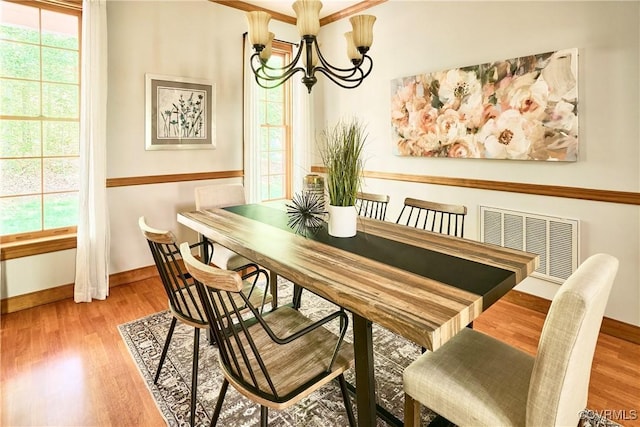 dining space with baseboards, a chandelier, wood finished floors, and visible vents
