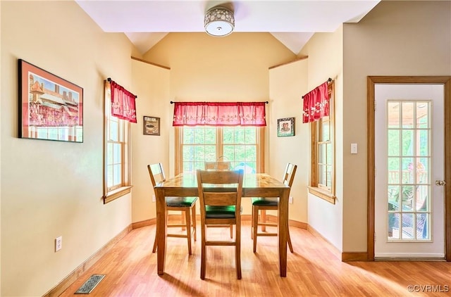 dining area featuring baseboards, vaulted ceiling, and light wood finished floors