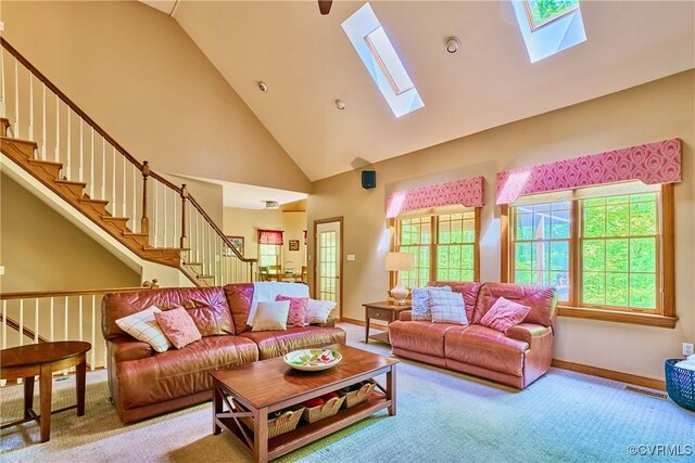 living room with a skylight, high vaulted ceiling, stairway, and carpet