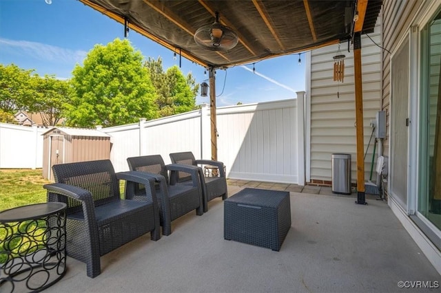 view of patio / terrace with a storage unit, a fenced backyard, a ceiling fan, and an outdoor structure