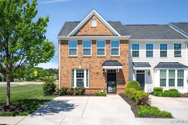 townhome / multi-family property with a front yard and brick siding