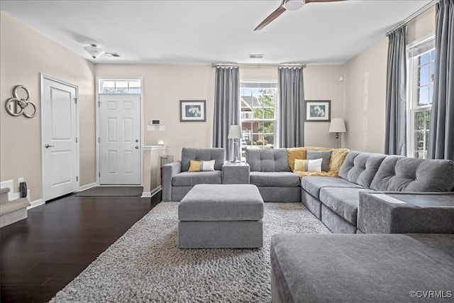 living room with dark wood-type flooring, baseboards, and ceiling fan