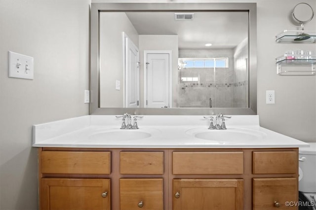 full bath featuring double vanity, a sink, a stall shower, and toilet