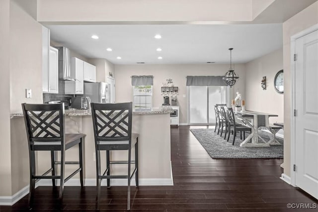 kitchen featuring stainless steel fridge, a peninsula, recessed lighting, white cabinetry, and dark wood-style floors