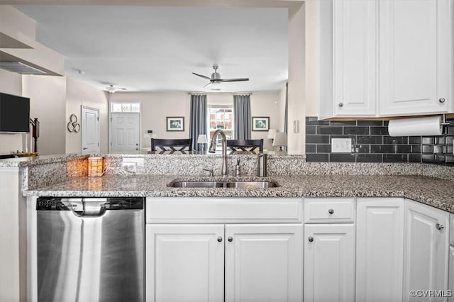 kitchen with stainless steel dishwasher, a ceiling fan, stone countertops, white cabinets, and a sink