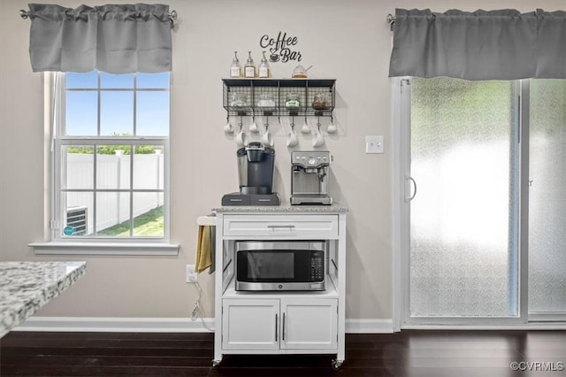 room details featuring baseboards, stainless steel microwave, fridge, and wood finished floors
