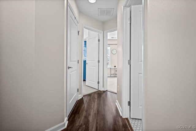 corridor with baseboards, visible vents, and wood finished floors